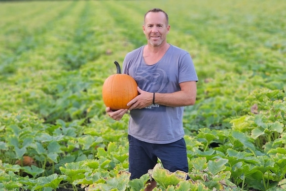 Ein Mensch steht auf einem Feld und hält einen Kürbis.